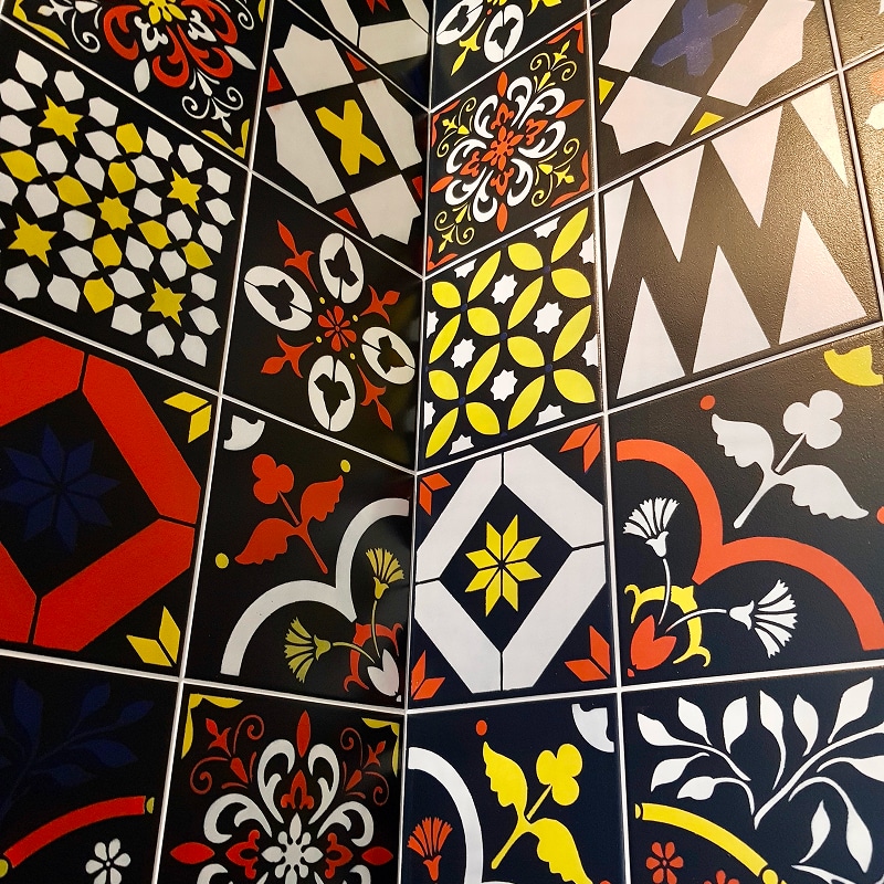 Carreaux de Ciment Colorés aux Motifs Géométriques Variés Gros plan sur un coin de mur avec des carreaux de ciment aux motifs géométriques et floraux colorés.