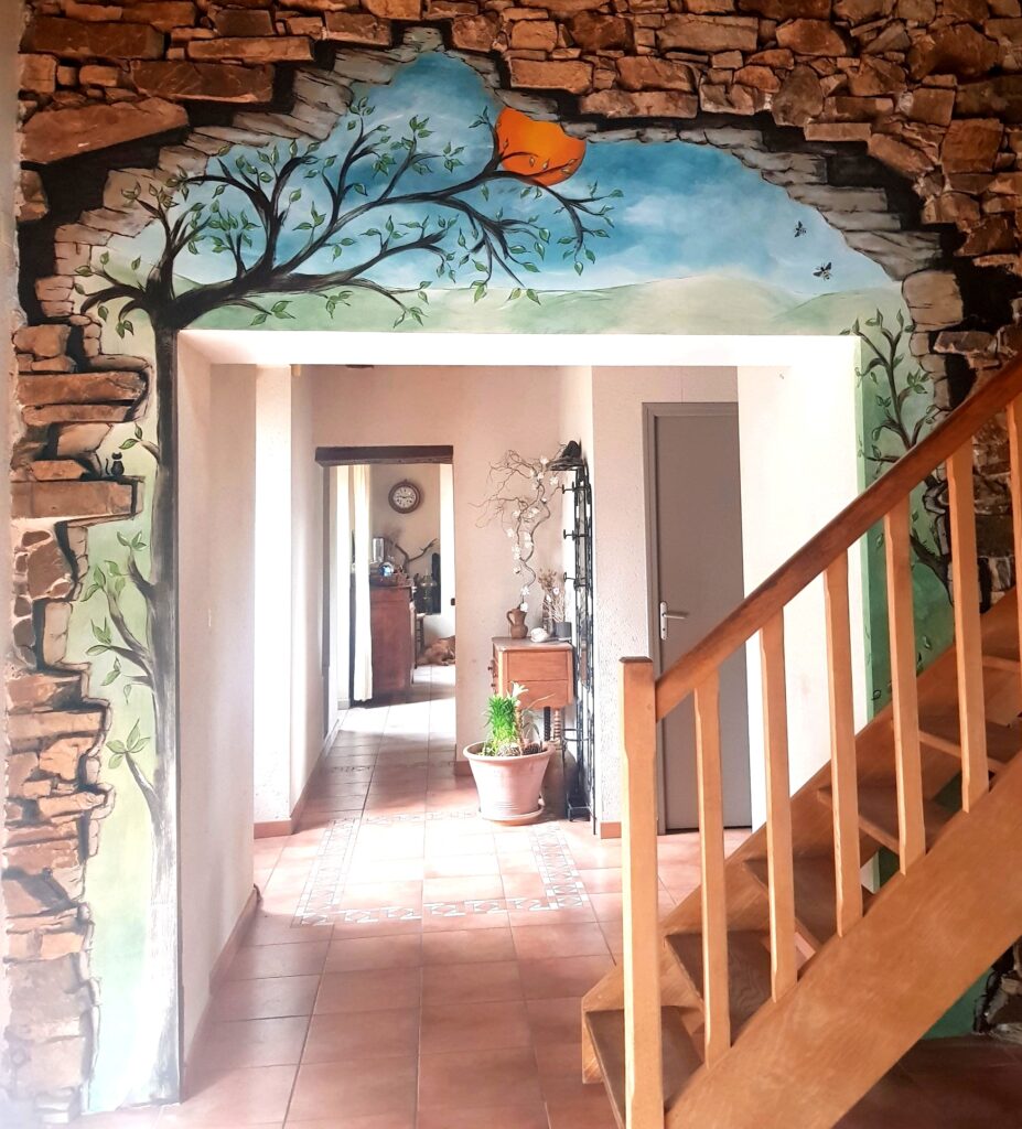 Fresque Murale Trompe-l'œil avec Arbre et Escalier Fresque murale trompe-l'œil d'un arbre et ciel bleu encadrant une porte, escalier en bois et intérieur chaleureux.