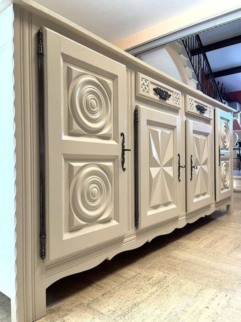 Buffet sculpté beige aux motifs circulaires et losanges avec ferrures noires rustiques.