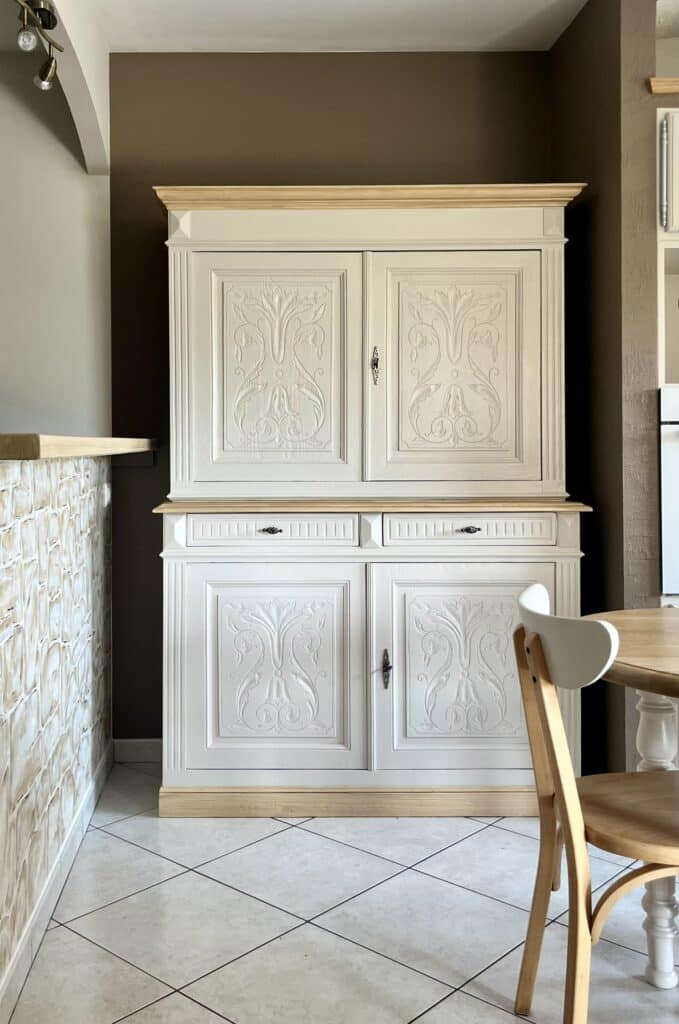 Buffet vaisselier blanc avec motifs sculptés et accents en bois clair dans un intérieur moderne.