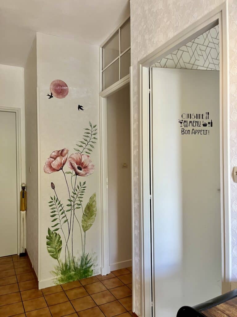 Mural coquelicots roses et texte 'CUISINE MENU Bon Appétit !' sur porte de cuisine vitrée.