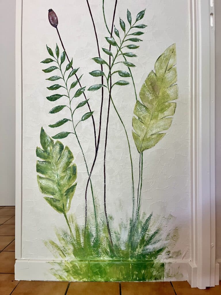 Fresque de feuillage vert et bourgeon sur mur blanc texturé.