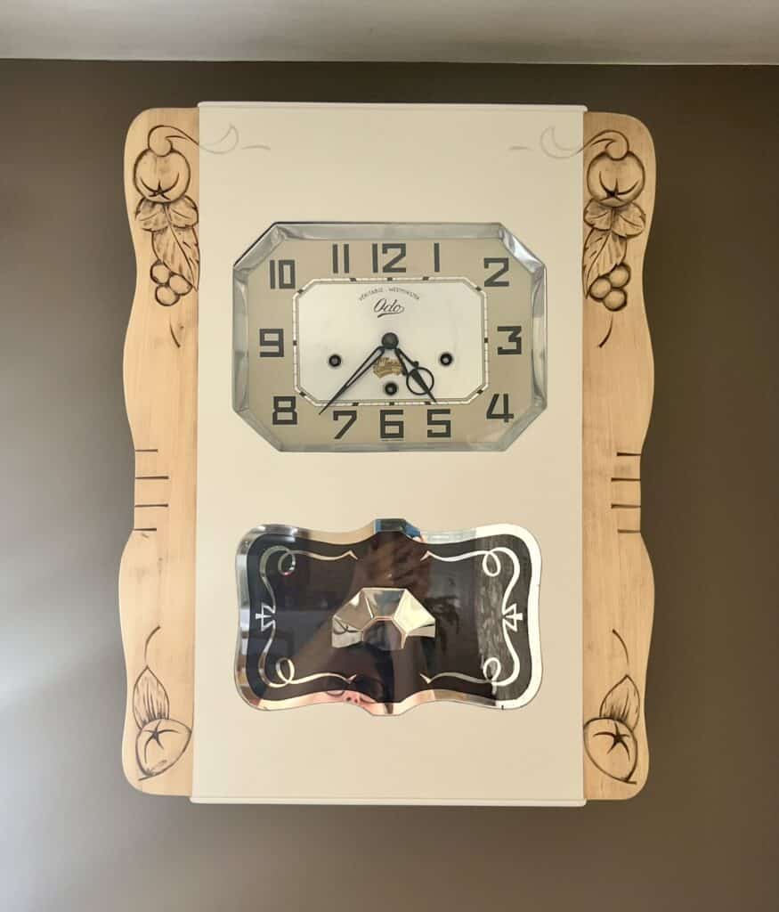 Horloge murale vintage Odo Westminster en bois sculpté avec cadran octogonal et chiffres noirs.