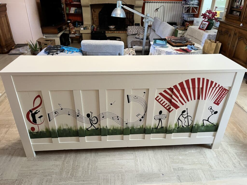 Buffet blanc avec fresque de musiciens stylisés, notes et accordéon rouge sur herbe peinte.