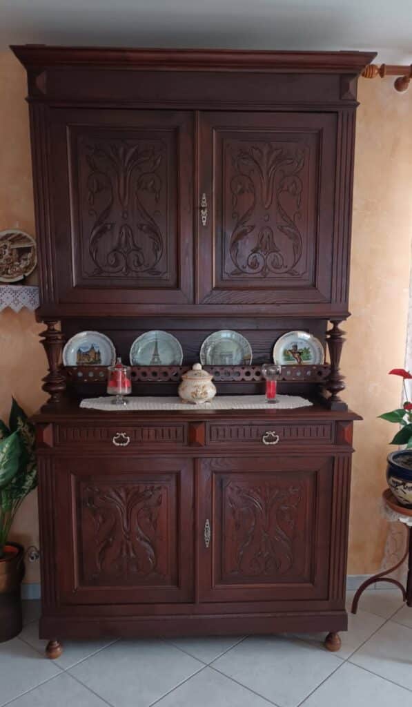 Vaisselier ancien en bois sculpté : charme et tradition Buffet vaisselier ancien en bois sculpté avec assiettes décoratives de Paris sur son étagère centrale.