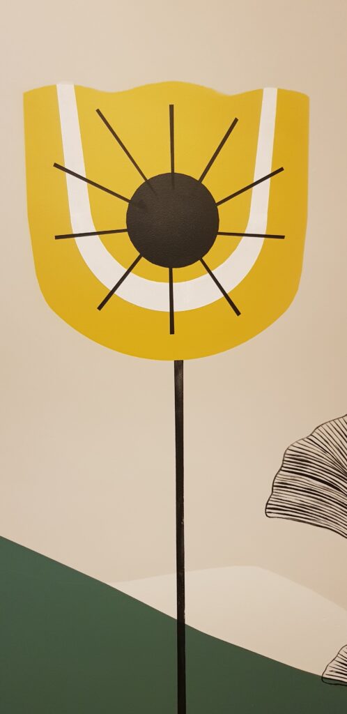 Fleur stylisée jaune et noire, style scandinave minimaliste sur mur beige.