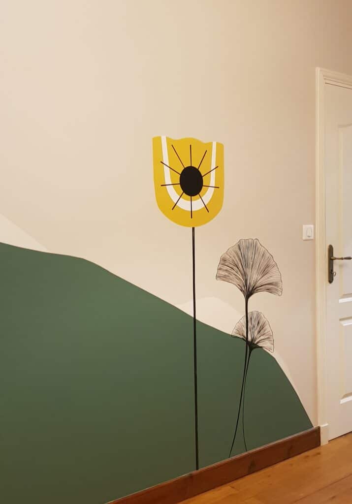 Peinture Murale Design : Fleur Jaune et Ginkgo Minimaliste Fresque murale minimaliste : fleur jaune stylisée et feuilles de ginkgo noires sur fond beige et colline verte.